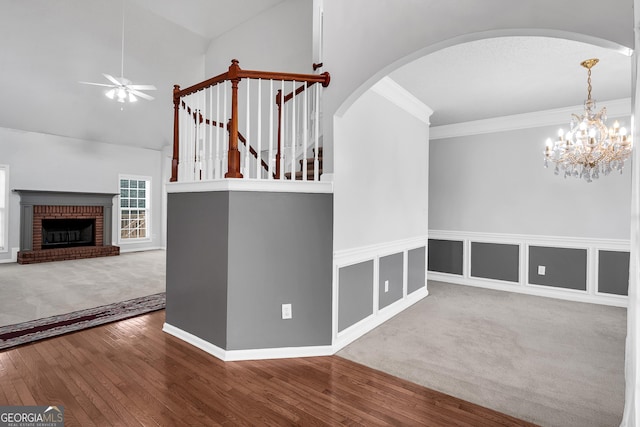 interior space with wood finished floors, ceiling fan with notable chandelier, arched walkways, and a fireplace