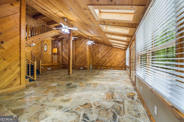 339 Ben Loudermilk Rd, Mount Airy, GA 30563 - interior space with wooden walls, stone floors, ceiling fan, vaulted ceiling with skylight, and baseboards