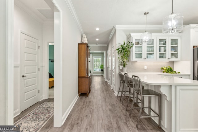 107 Amanda Trce, Kingsland, GA 31548 - kitchen featuring crown molding, a breakfast bar area, white cabinetry, light countertops, and glass insert cabinets