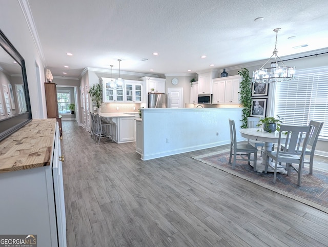107 Amanda Trce, Kingsland, GA 31548 - kitchen with stainless steel appliances, a chandelier, glass insert cabinets, white cabinetry, and wood finished floors