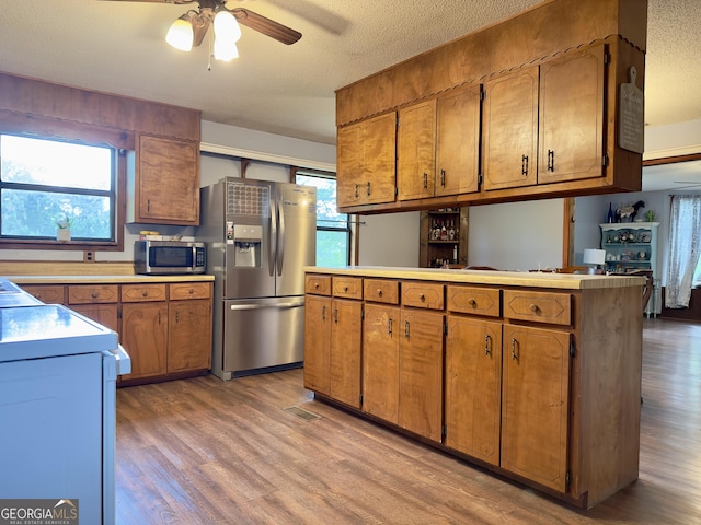1685 Ridgeway Rd, Lafayette, GA 30728 - kitchen featuring appliances with stainless steel finishes, light wood-style floors, brown cabinets, ceiling fan, and healthy amount of natural light