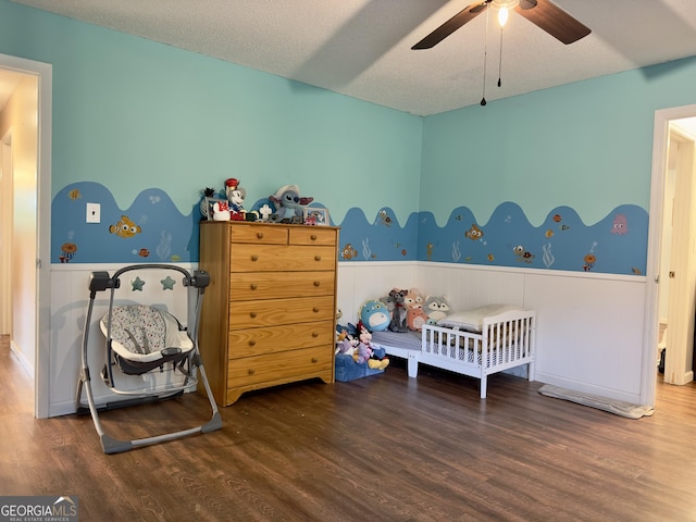 1685 Ridgeway Rd, Lafayette, GA 30728 - bedroom featuring wainscoting, a crib, wood finished floors, a textured ceiling, and a ceiling fan