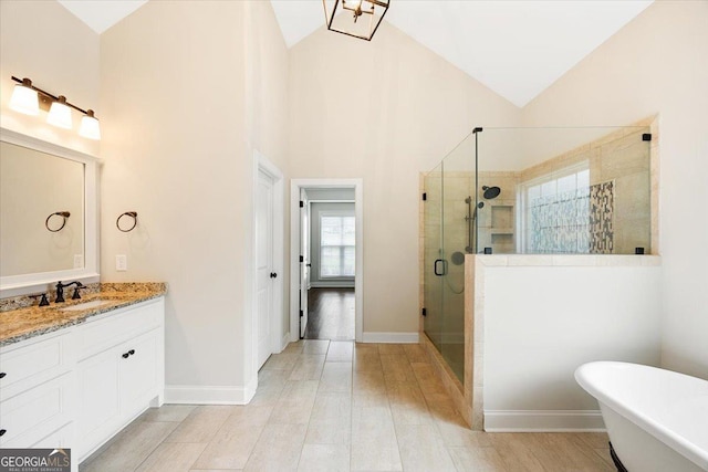 135 Broadleaf Dr, Macon, GA 31210 - full bath featuring vanity, baseboards, high vaulted ceiling, a soaking tub, and a shower stall