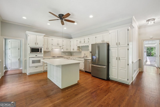 kitchen featuring appliances with stainless steel finishes, a sink, a center island, light countertops, and a ceiling fan