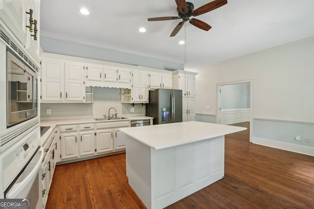 kitchen with stainless steel appliances, a sink, a center island, white cabinetry, and light countertops