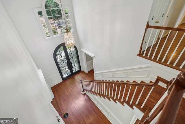 entrance foyer with a decorative wall, stairway, wood finished floors, and a towering ceiling