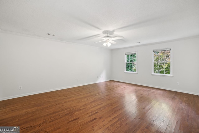 spare room featuring a ceiling fan, wood finished floors, crown molding, and baseboards