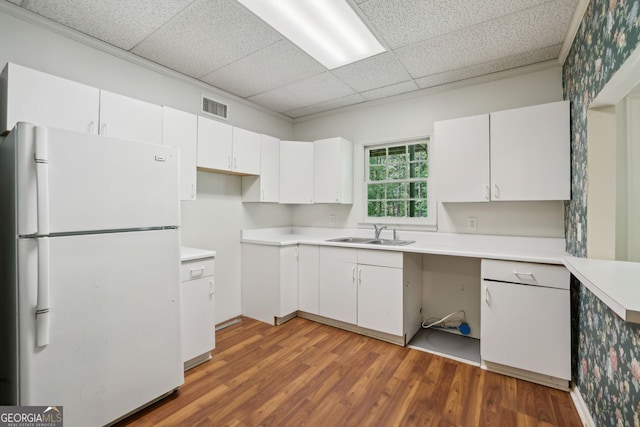 kitchen with freestanding refrigerator, a paneled ceiling, a sink, wood finished floors, and white cabinets