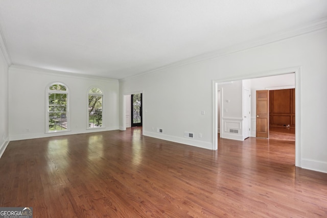 unfurnished living room featuring crown molding, wood finished floors, and baseboards