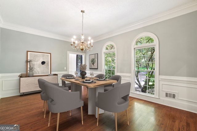 dining area with a chandelier, wainscoting, ornamental molding, wood finished floors, and a decorative wall