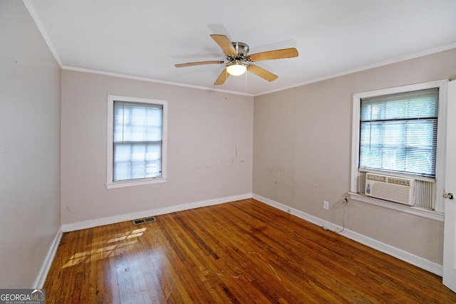 empty room featuring wood finished floors, visible vents, a wealth of natural light, and cooling unit