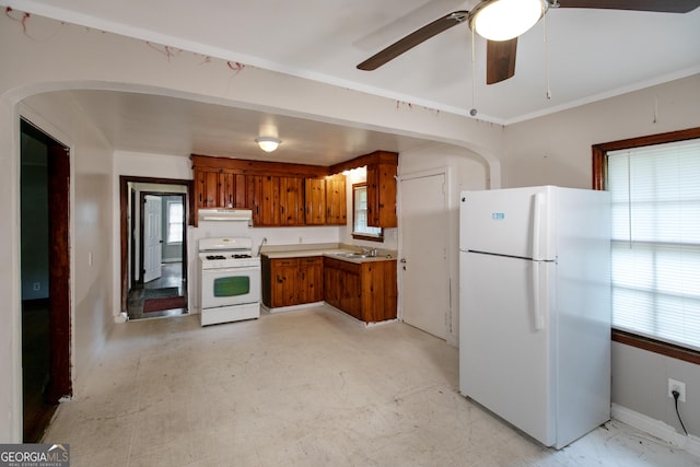 kitchen featuring brown cabinetry, white appliances, ceiling fan, under cabinet range hood, and a sink
