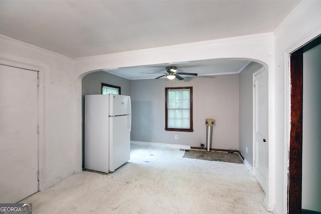 interior space featuring baseboards, arched walkways, ceiling fan, and ornamental molding