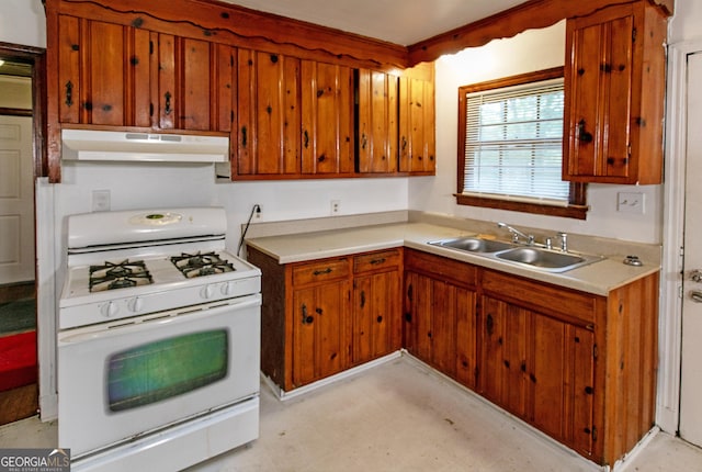 kitchen with under cabinet range hood, brown cabinets, white gas range oven, and a sink
