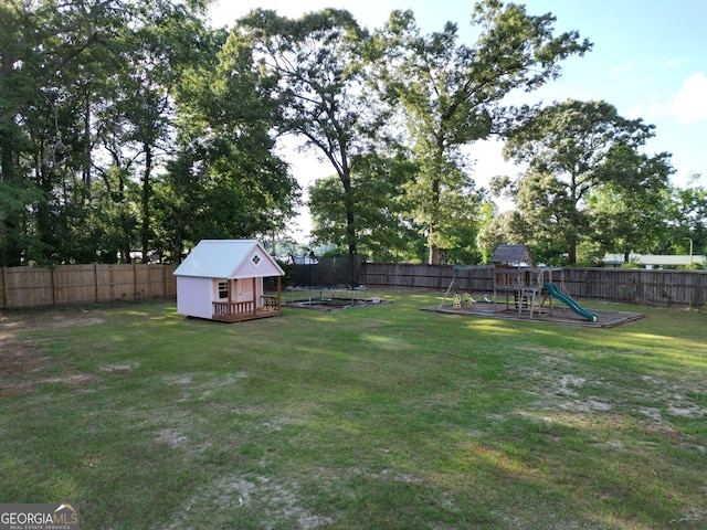 view of yard featuring a fenced backyard, an outbuilding, a playground, a trampoline, and a storage shed