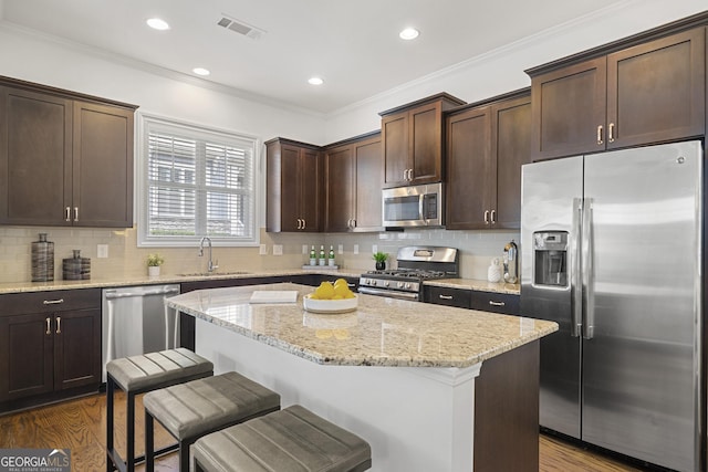 kitchen with a sink, appliances with stainless steel finishes, dark brown cabinetry, and dark wood-type flooring