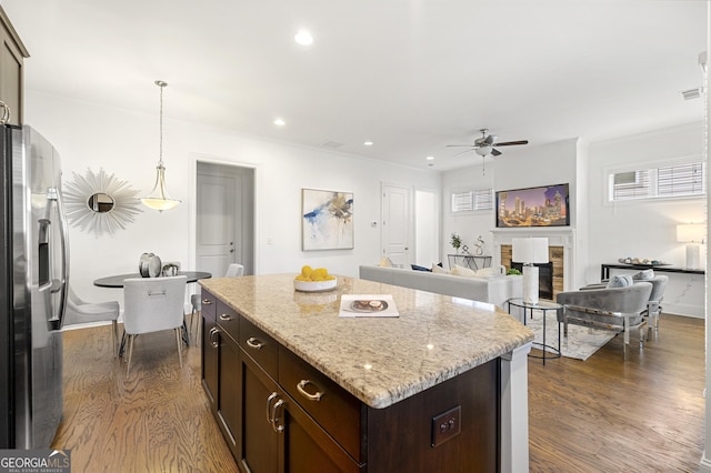 kitchen with dark wood finished floors, ceiling fan, a kitchen island, and stainless steel refrigerator with ice dispenser