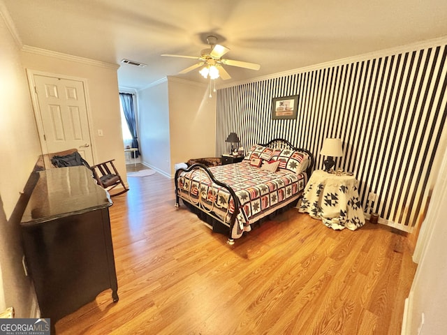 bedroom with ceiling fan, visible vents, crown molding, wood finished floors, and baseboards