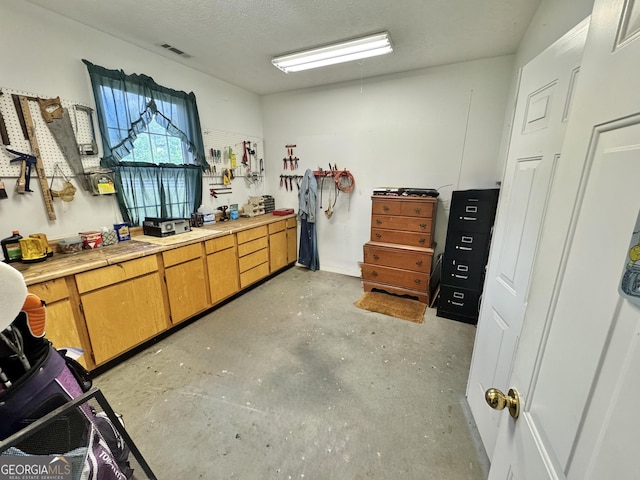misc room featuring concrete floors, a textured ceiling, and visible vents