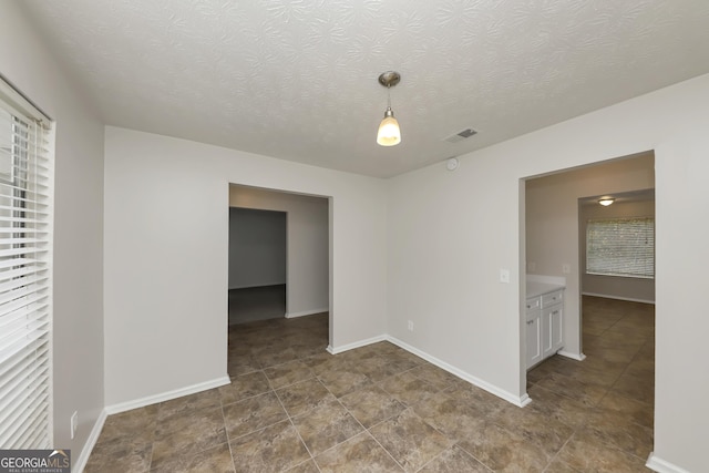 spare room with a textured ceiling, visible vents, and baseboards