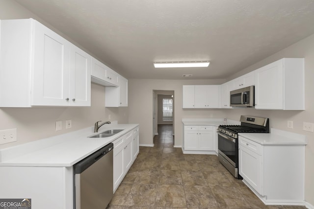 kitchen with a sink, white cabinetry, light countertops, baseboards, and appliances with stainless steel finishes
