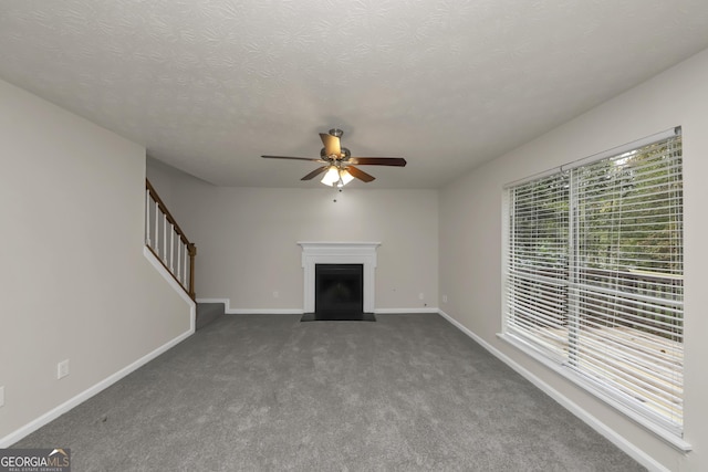 unfurnished living room featuring stairs, a fireplace, carpet floors, a ceiling fan, and baseboards