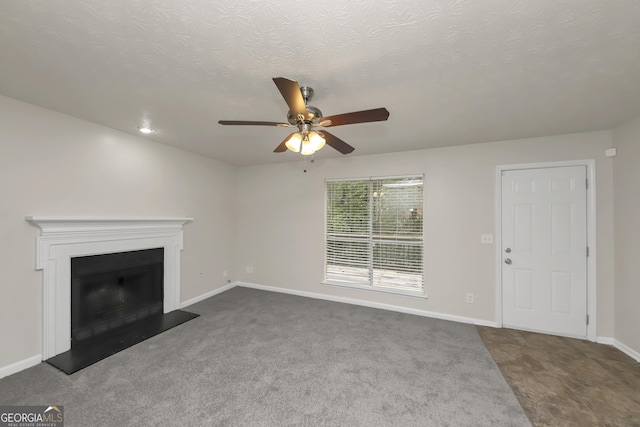 unfurnished living room with a textured ceiling, a fireplace, carpet floors, a ceiling fan, and baseboards