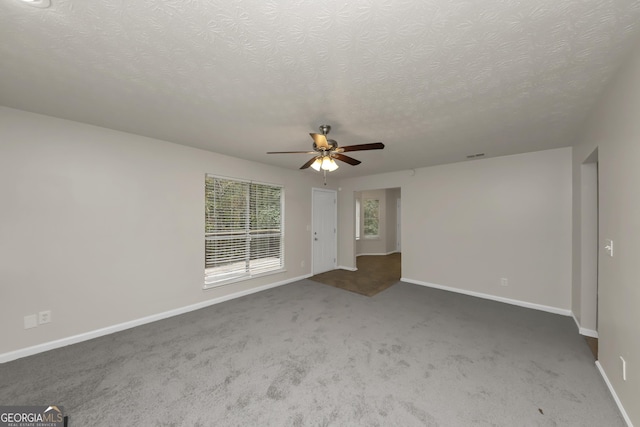 carpeted empty room with a textured ceiling, visible vents, baseboards, and ceiling fan