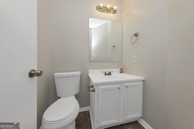 bathroom featuring toilet, baseboards, and vanity