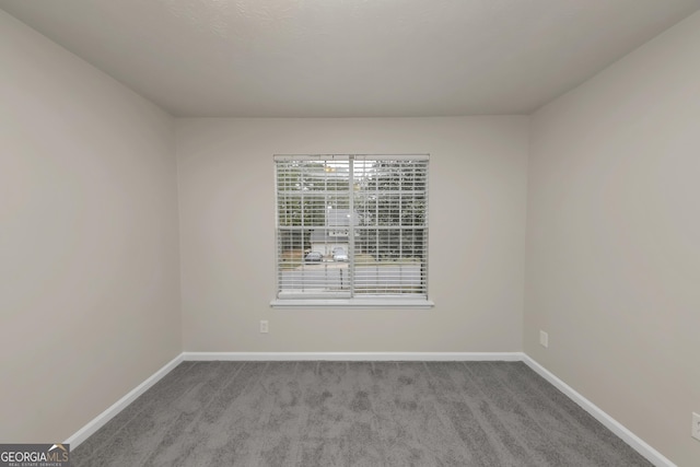 carpeted empty room featuring baseboards