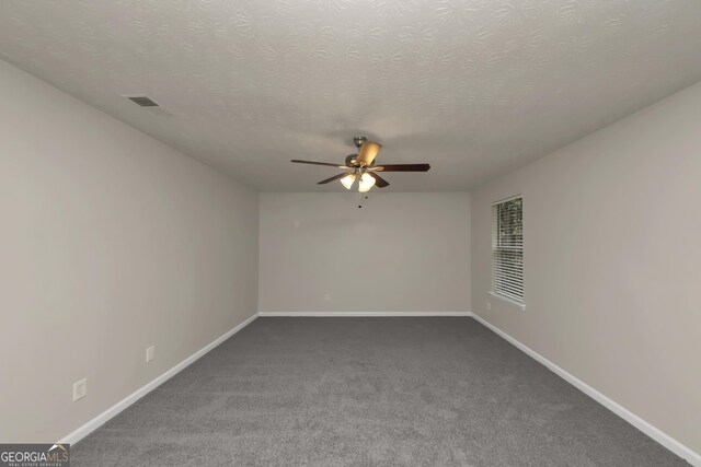 carpeted spare room featuring a textured ceiling, baseboards, a ceiling fan, and visible vents