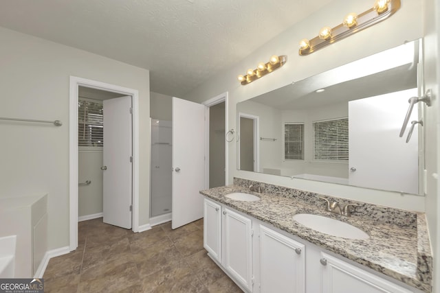 bathroom with double vanity, a bath, baseboards, and a sink