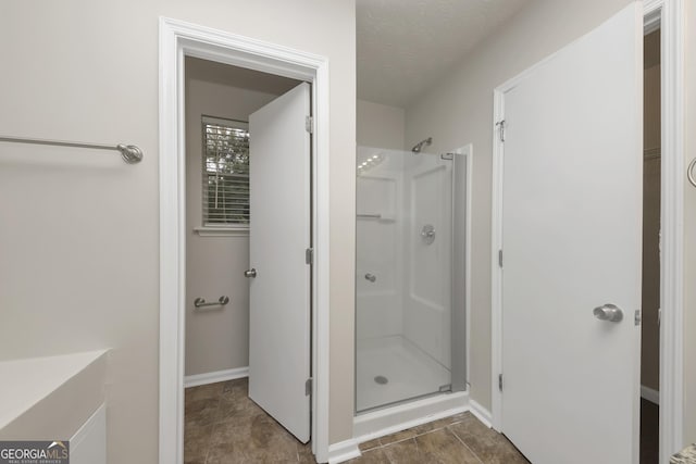 bathroom with a shower stall and baseboards