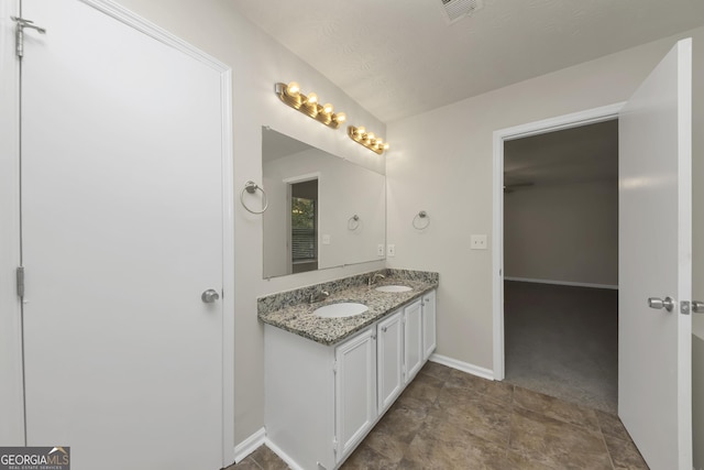 bathroom with double vanity, visible vents, baseboards, and a sink