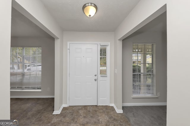 foyer entrance featuring baseboards and a textured ceiling