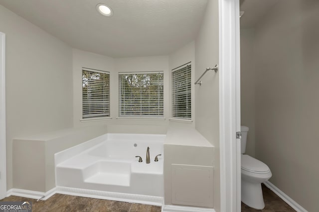 full bath featuring a bath, toilet, and baseboards