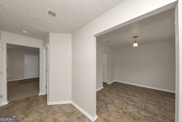 unfurnished room featuring a textured ceiling, baseboards, and visible vents