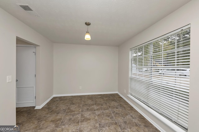 empty room with a textured ceiling, visible vents, and baseboards