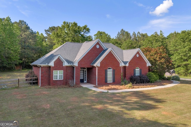 view of front facade featuring fence, a front lawn, and brick siding