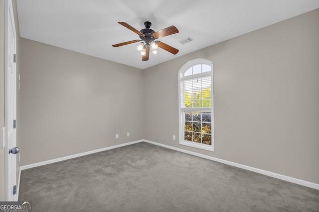 carpeted spare room featuring visible vents, a ceiling fan, and baseboards