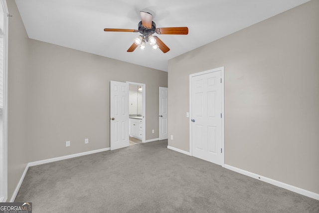 unfurnished bedroom with baseboards, connected bathroom, carpet, and ceiling fan