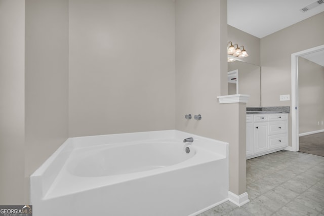 bathroom featuring visible vents, baseboards, a garden tub, and vanity
