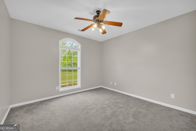 carpeted spare room featuring baseboards, visible vents, and ceiling fan