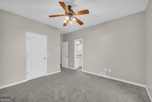 unfurnished bedroom featuring baseboards, ensuite bath, carpet floors, and visible vents