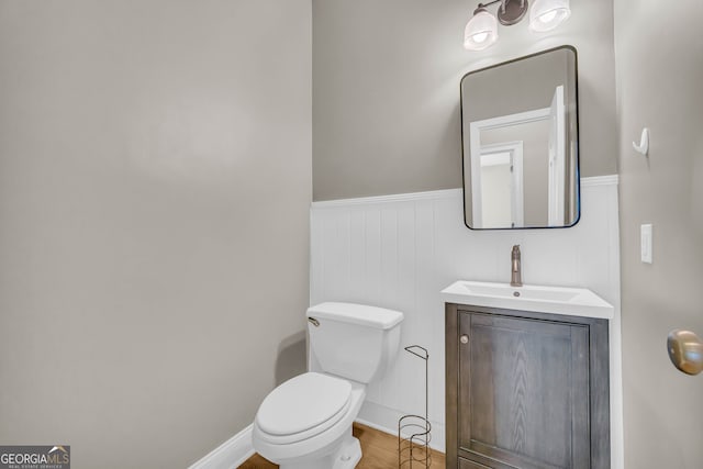 bathroom with vanity, wainscoting, toilet, and wood finished floors