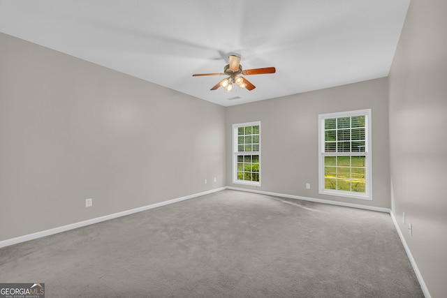 carpeted spare room featuring baseboards and a ceiling fan