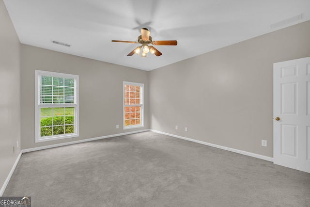 carpeted spare room featuring baseboards, ceiling fan, and visible vents
