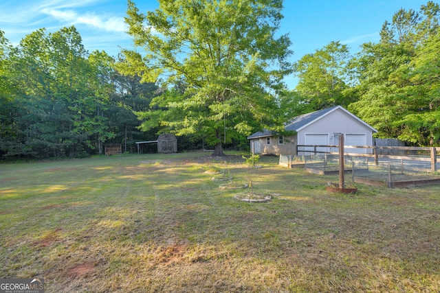 view of yard featuring a garage, fence, an outdoor structure, and a storage unit
