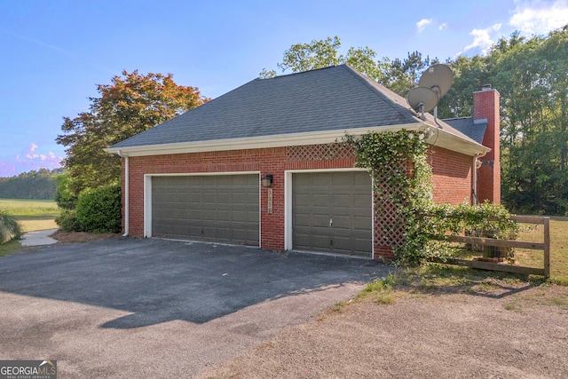 garage featuring fence and aphalt driveway