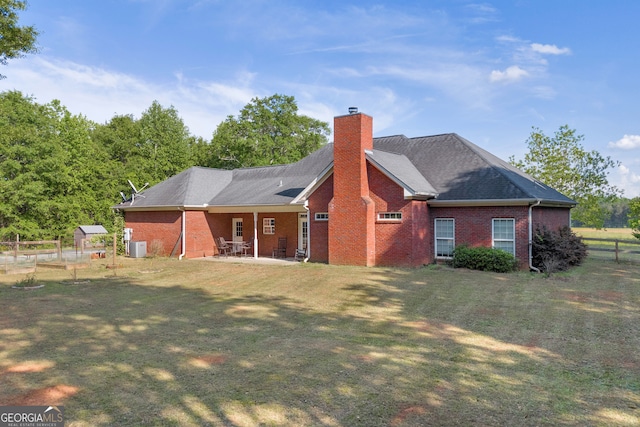 exterior space with brick siding, a patio, a yard, and a chimney